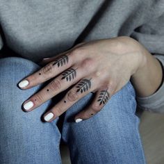 a woman's hand with tattoos on her left wrist and fingers, sitting on the floor