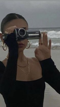 a woman taking a photo on the beach with her cell phone in front of her face