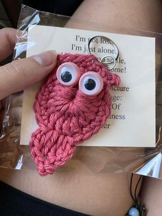 a person holding up a piece of yarn with googly eyes on it's belly