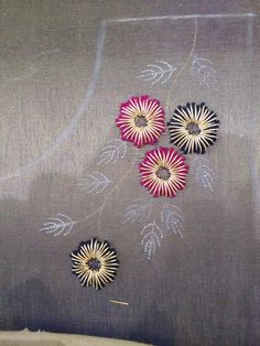 three flowers on a gray background with white and pink designs in the middle, sitting next to each other