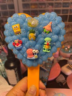 a hand holding a yellow toothbrush with cartoon characters on it and balloons in the background