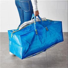 a person holding a blue bag with clothes in it and the bottom part of their pants