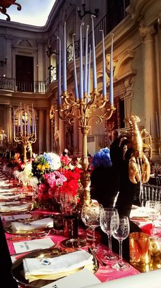 a long table is set with red, white and blue flowers in front of an ornate chandelier