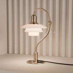 a lamp that is sitting on top of a table in front of a curtained wall