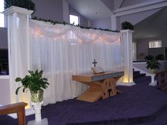 an empty church with purple carpet and white drapes on the windowsill, decorated with greenery