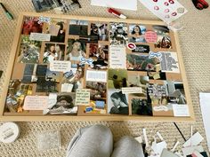 a cork board covered in pictures and magnets on the floor next to a pair of shoes