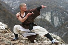 a man is standing on top of a mountain with his arms out in the air