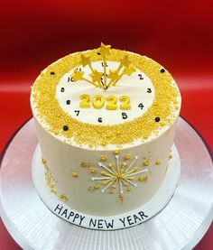 a white and yellow birthday cake with gold decorations on the top that says happy new year