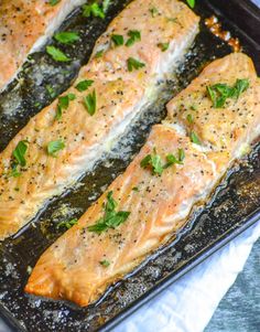 two salmon fillets in a baking pan with herbs on the top and seasoning