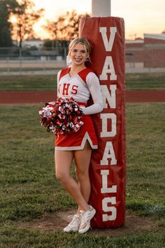 a cheerleader is posing next to a sign