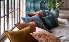 a bunch of pillows sitting on top of a couch in front of a large window