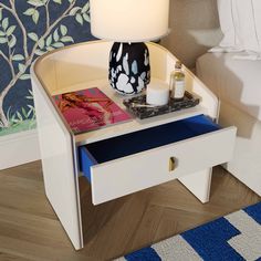 a night stand with a lamp, book and magazine on it