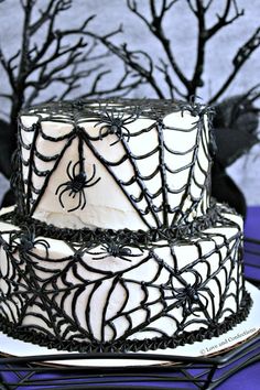 a spider web cake with white frosting and black icing on a purple tablecloth