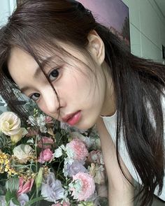 a woman with long hair and flowers in front of her face looking at the camera