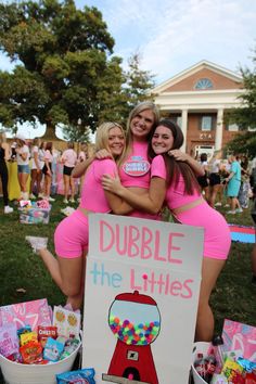 two girls hugging each other in front of a sign that says double the littles