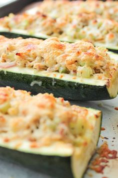 zucchini stuffed with cheese and other toppings on a baking sheet, ready to go into the oven