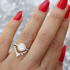 a woman's hand with red nail polish and a diamond ring on her finger