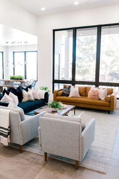 a living room with couches, chairs and tables in front of large glass windows