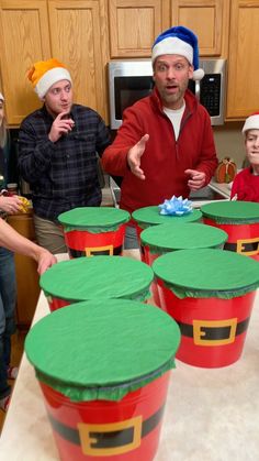 a group of people wearing christmas hats standing in front of buckets filled with food