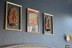 three paintings on the wall above a bed in a room with blue walls and gold trim