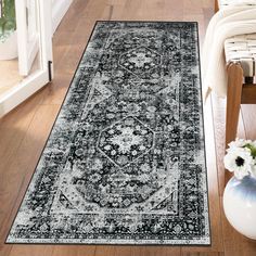 a black and white area rug with an ornate design on the floor next to a chair