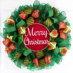 a christmas wreath with green mesh and red bows on the front door that says merry christmas