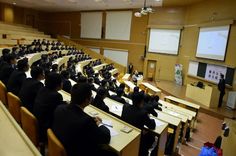 an empty lecture hall with people sitting at desks in front of the projector screen