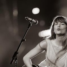 a black and white photo of a woman with her eyes closed while playing the guitar