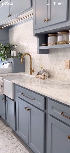 a kitchen with blue cabinets and marble counter tops, gold faucets and brass pulls