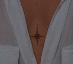 a person with a small star tattoo on their chest and behind her is a white shirt