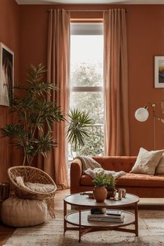 a living room with an orange couch, chair and potted plant in the corner