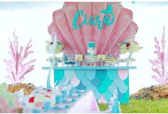 an ocean themed dessert table with pink and blue decorations on the top, under a tent