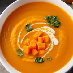 a white bowl filled with carrot soup and garnished with parsley