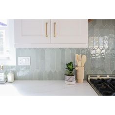 a kitchen with white cabinets and marble counter tops is pictured in this image, there are two wooden utensils on the stovetop