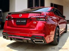 the rear end of a red car parked in front of a building