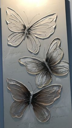 three butterflies are shown on a metal plaque