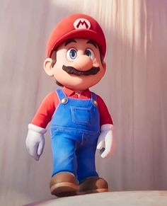 a toy mario is standing on top of a white object with blue overalls and a moustache