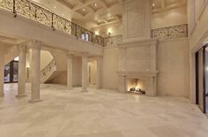 a large living room with white marble flooring and columns on either side of the fireplace