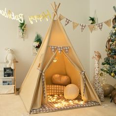 a teepee tent sitting next to a christmas tree in a child's room