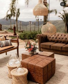 a living room filled with lots of furniture next to a lush green hillside covered in palm trees