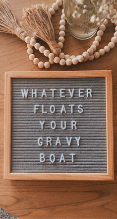 a wooden sign that says whatever floats your gray boat on it next to some tassels