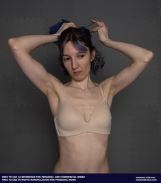 a woman in a tan bra posing for the camera with her hands on her head