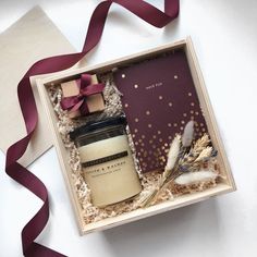 an open gift box containing a candle and some feathers