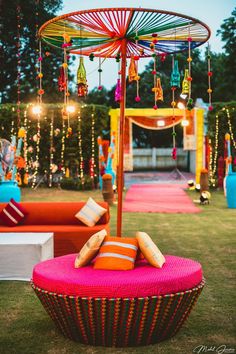 an umbrella sitting on top of a pink cushion in the grass next to couches