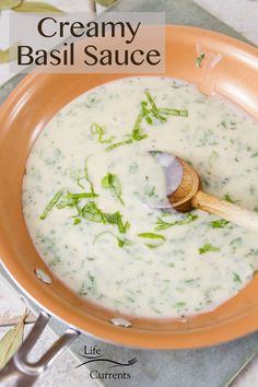 creamy basil sauce in an orange bowl with a wooden spoon on the side and text overlay that reads, creamy basil sauce