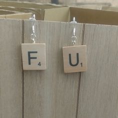 some type of earrings with the letters fu and f on them, hanging from hooks