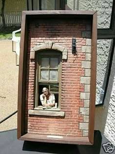 a brick building with a window and a person looking out the window from inside it