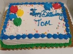 a birthday cake with white frosting and blue icing, on top of a cardboard box