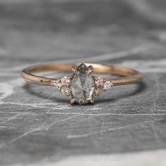 an engagement ring with three stones on top and two diamonds in the middle, sitting on a stone surface