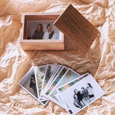 a wooden box filled with photos on top of a sheet of wax paper next to a pile of cards